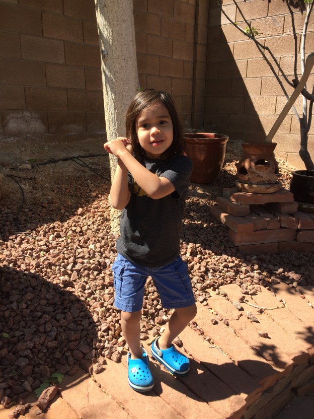 Jacson in his Star Wars shirt and Star Wars shoes standing in the sunshine