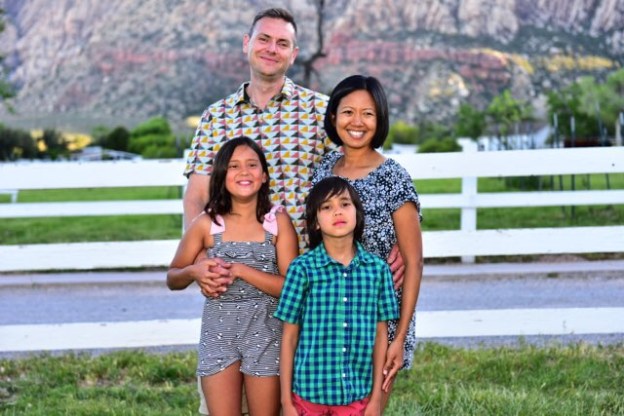 Rupp Family standing in front of a white ranch fence, with pasture and mountains in the background.