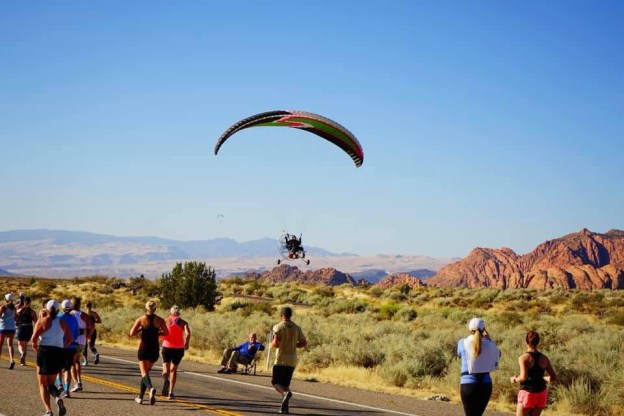image of a hang glider floating above St. George Marathon runners